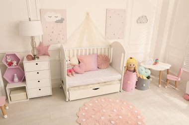 Bebek odasının içinde beşik ve oyuncaklar var.