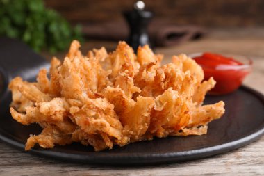 Ahşap masada servis edilen soslu kızarmış soğan, yakın plan.