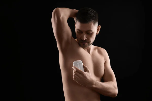 Hombre Guapo Aplicando Desodorante Sobre Fondo Negro — Foto de Stock