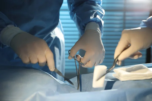 Professional surgeons with instruments performing operation in clinic, closeup