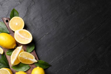 Siyah masa üzerinde yeşil yaprakları olan taze limonlar. Metin için boşluk