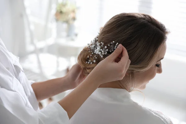 Professional stylist making wedding hairstyle for bride in salon