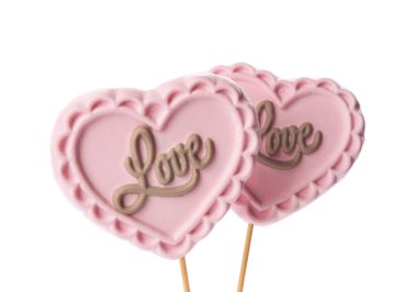 Beyaz arka planda çikolatadan yapılmış kalp şeklinde lolipoplar.