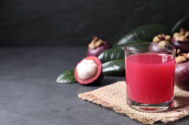 Karanlık masada cam içinde nefis taze mangosteen suyu, metin için yer.