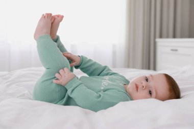 Küçük şirin bebek yumuşak battaniyeyle yatakta uzanıyor.