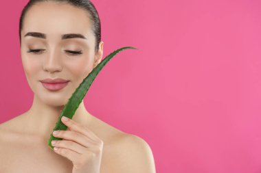 Pembe arka planda aloe vera yaprağı olan genç bir kadın. Metin için boşluk