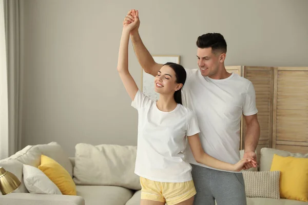 Happy couple in pyjamas dancing at home