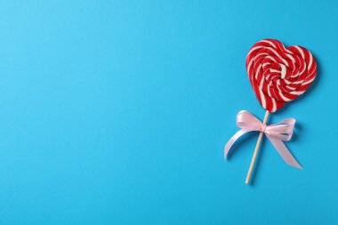Açık mavi arka planda tatlı kalp şeklinde lolipop, metin için yeri olan üst manzara. Sevgililer Günü kutlaması