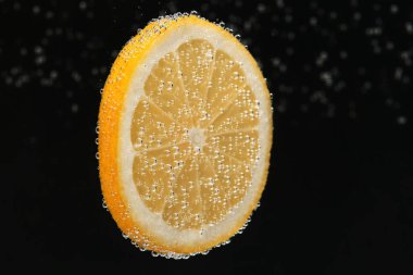 Siyah arka planda köpüklü suya limon dilimi. Citrus gazozu