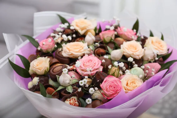 Beautiful food bouquet of sweets and flowers on light background