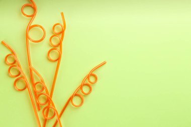 Yeşil arka planda turuncu plastik pipetler, düz yatış. Metin için boşluk