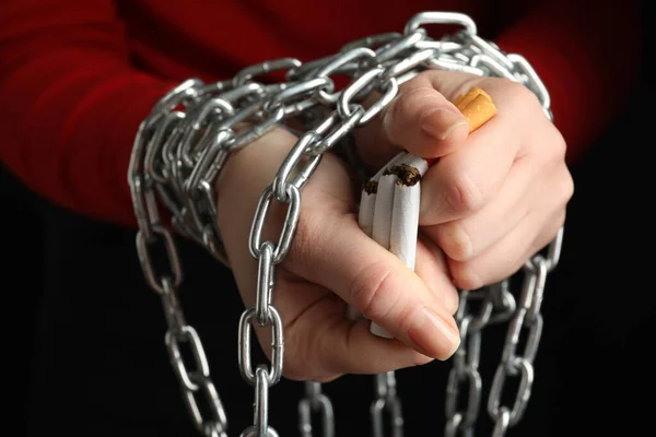 Woman with chain on hands breaking cigarettes, closeup. Quitting smoking concept