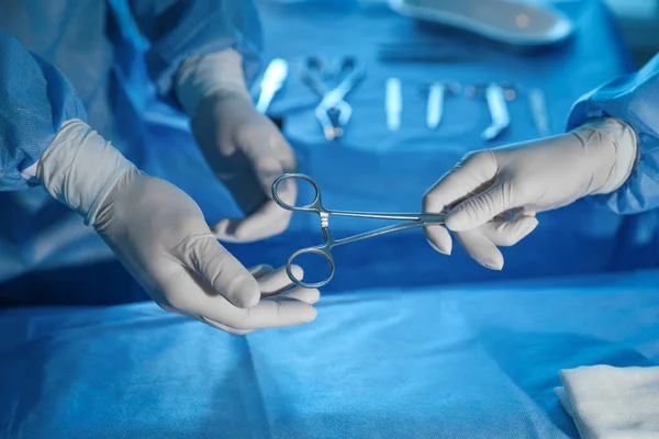 Professional surgeons with instruments performing operation in clinic, closeup