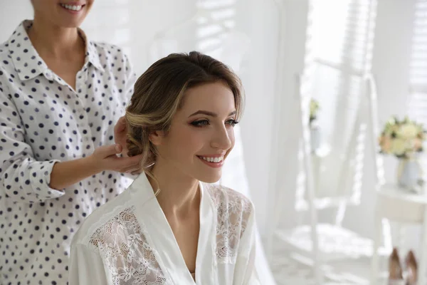 Professional stylist making wedding hairstyle for bride in salon