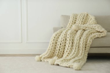 Işık duvarının yanındaki kanepede örülmüş merino yün ekose kumaş. Metin için boşluk