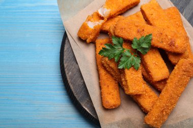 Açık mavi ahşap masada servis edilen maydanozlu taze ekmekli balık kroket. Metin için boşluk