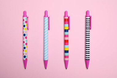 Stylish retractable pens on pink background, flat lay