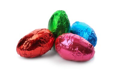 Beyaz arka planda parlak folyoya sarılı çikolatalı yumurtalar.