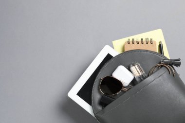 Stylish urban backpack with different items on grey background, top view. Space for text