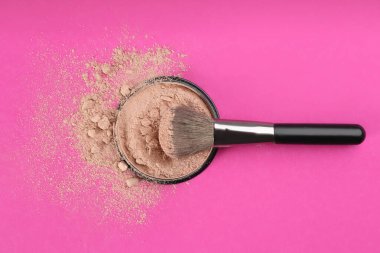 Makeup brush and face powder on bright pink background, flat lay