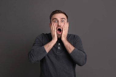Portrait of emotional young man on grey background. Personality concept
