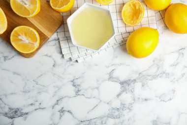 Freshly squeezed lemon juice on white marble table, flat lay. Space for text