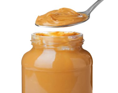 Taking spoon of delicious peanut butter on white background