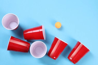 Plastik bardaklar ve top açık mavi arka planda, düz yerde. Bira pong oyunu