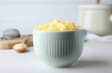 Bowl of Ghee butter on white wooden table, closeup