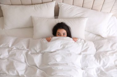 Genç bir kadın sıcak beyaz battaniyenin altında saklanıyor.