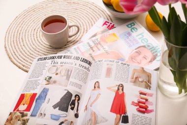 Farklı yaşam tarzı dergileri ve beyaz masada çay.