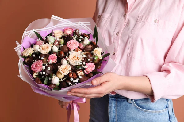 Woman with beautiful food bouquet on brown background, closeup