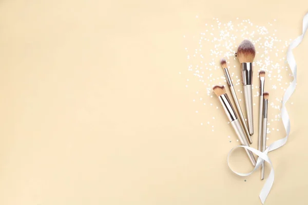 Flat lay composition with makeup brushes on beige background, space for text