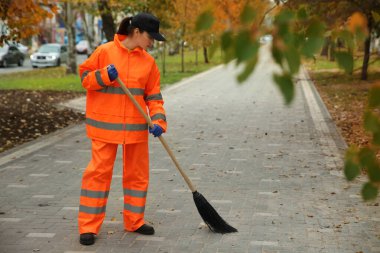 Sonbahar günü yaprakları süpüren sokak temizleyicisi.