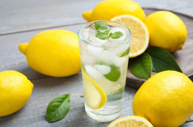 Soğuk taze limonata ve gri ahşap masada meyveler.