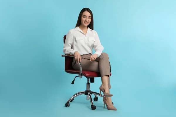 Młoda Bizneswoman Siedzi Wygodnym Fotelu Biurowym Turkusowym Tle — Zdjęcie stockowe