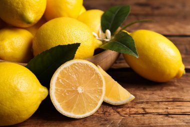 Tahta masada yeşil yapraklı taze limonlar, yakın plan.