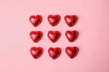 Pembe arka planda kalp şeklinde çikolata şekerlemeleri, düz yatış. Sevgililer Günü hediyesi
