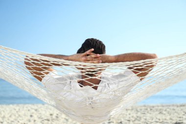 Sahilde hamakta dinlenen bir adam. Yaz tatili