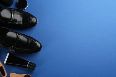Düz kompozisyon, ayakkabı bakım aksesuarları ve mavi arka planda ayakkabılar. Metin için boşluk