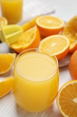 Taze meyve suyu, portakallar ve ahşap masa.