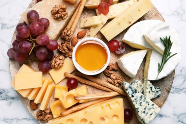 Ballı peynir tabağı, beyaz mermer masada üzüm ve fındık.