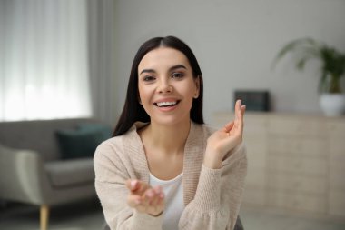 Güzel genç bir kadın, odada webinar yönetiyor, kamera manzaralı.