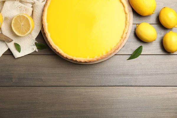 Delicious homemade lemon pie and fruits on wooden table, flat lay. Space for text