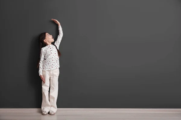 Эмоциональный Маленький Ребенок Измеряет Свой Рост Возле Черной Стены Помещении — стоковое фото