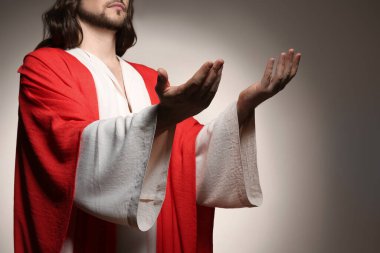 İsa bej arka planda ellerini uzatıyor, yakın plan.