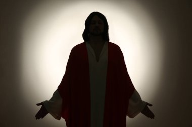 İsa 'nın silueti. Renkli arka planda kolları açık.