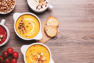Farklı lezzetli krema çorbaları ve ahşap masa üzerinde ekmek, düz yatış. Metin için boşluk