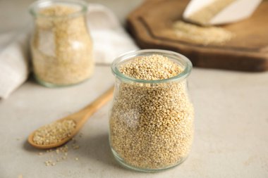 Açık gri masada beyaz kinoalı kavanoz.