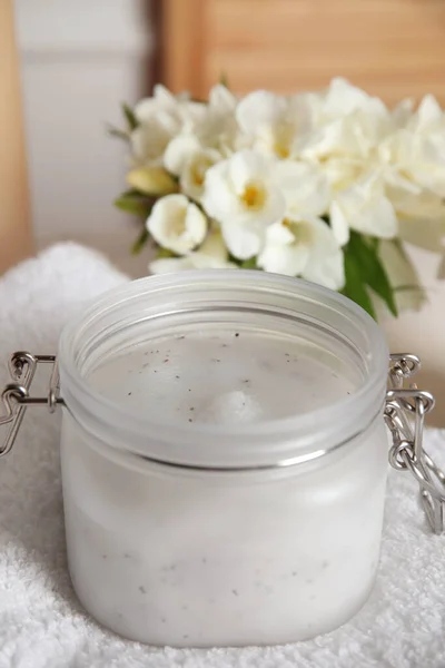 Jar of natural exfoliating salt scrub on white towel